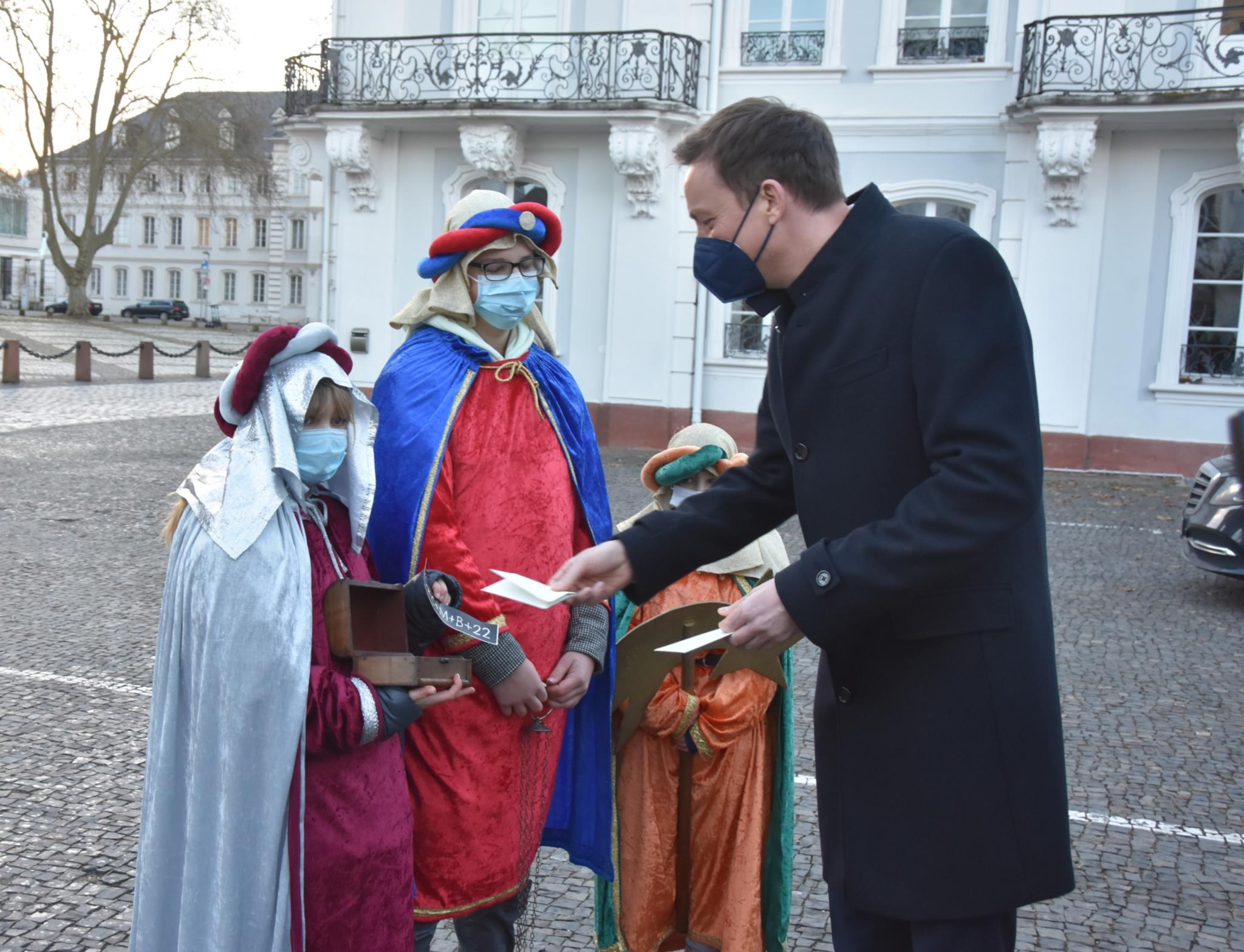 Ministerpräsident Hans gibt Charlotta, Leonhard und Violetta aus Völklingen eine Spende. Foto: uk
