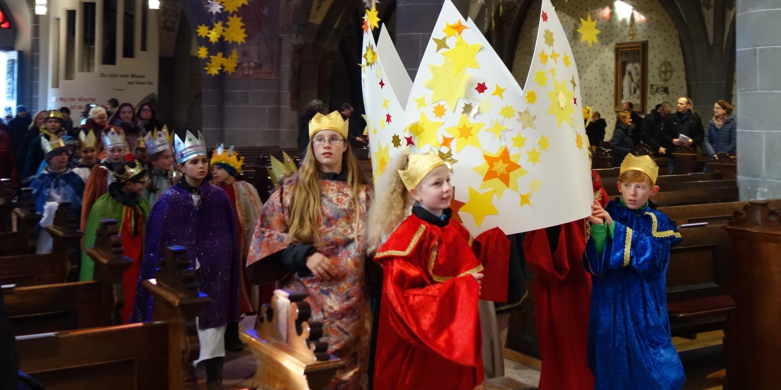 Die Sternsinger tragen eine große Krone in die Pfarrkirche.