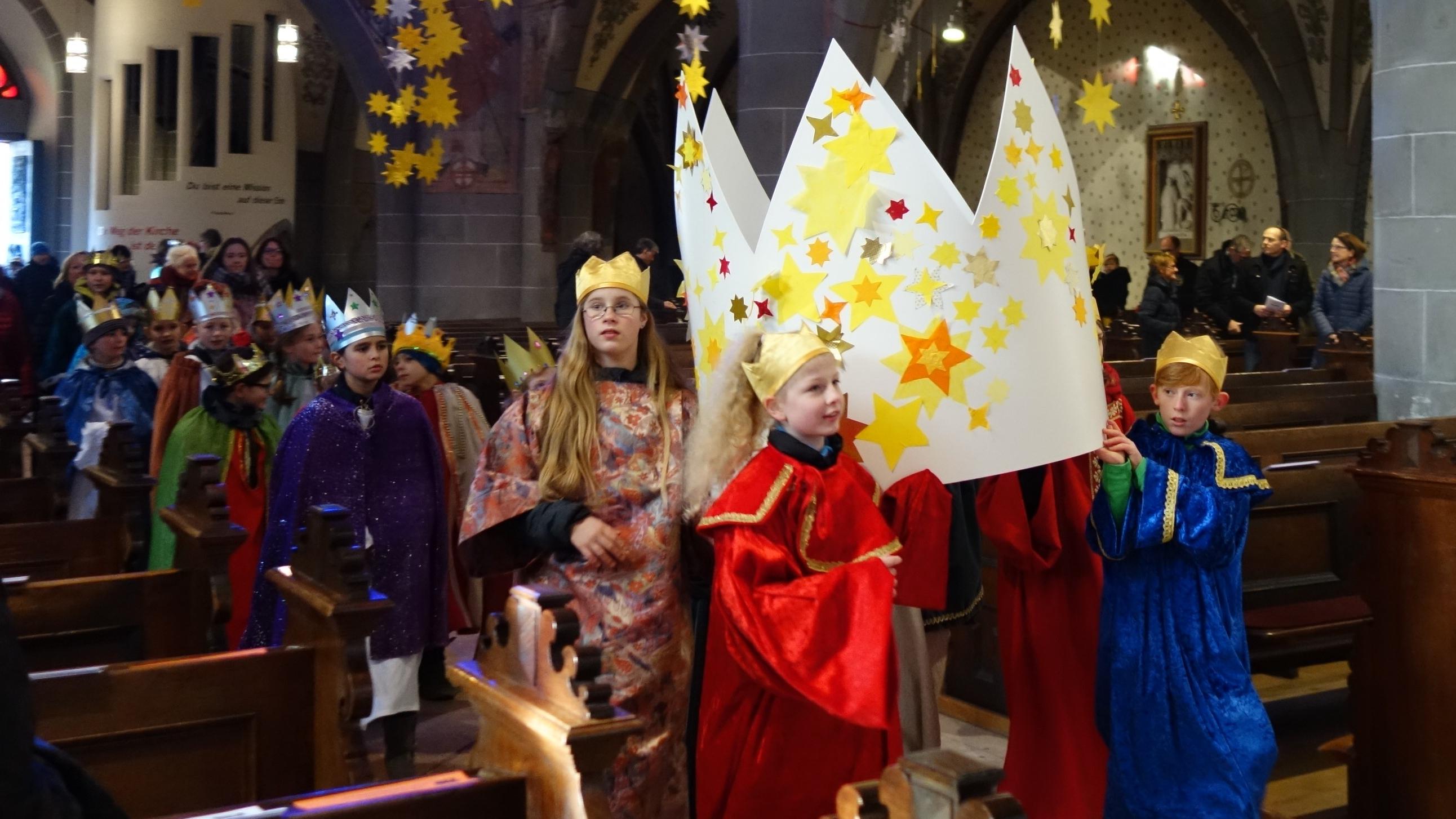 Die Sternsinger tragen eine große Krone in die Pfarrkirche.