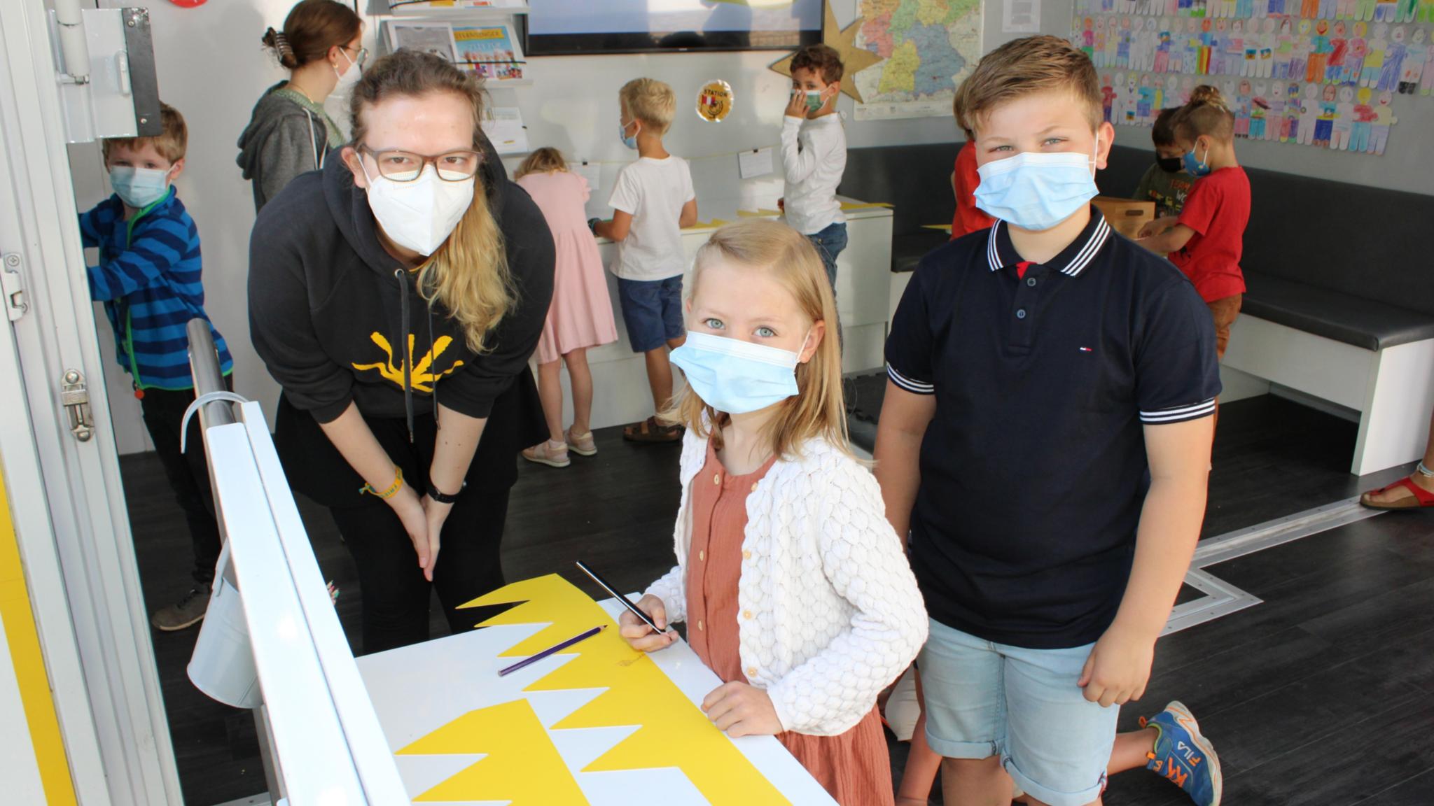 Isabell Mahler vom Kindermissionswerk bastelt mit Lena und Jan ganz persönliche Kronen.