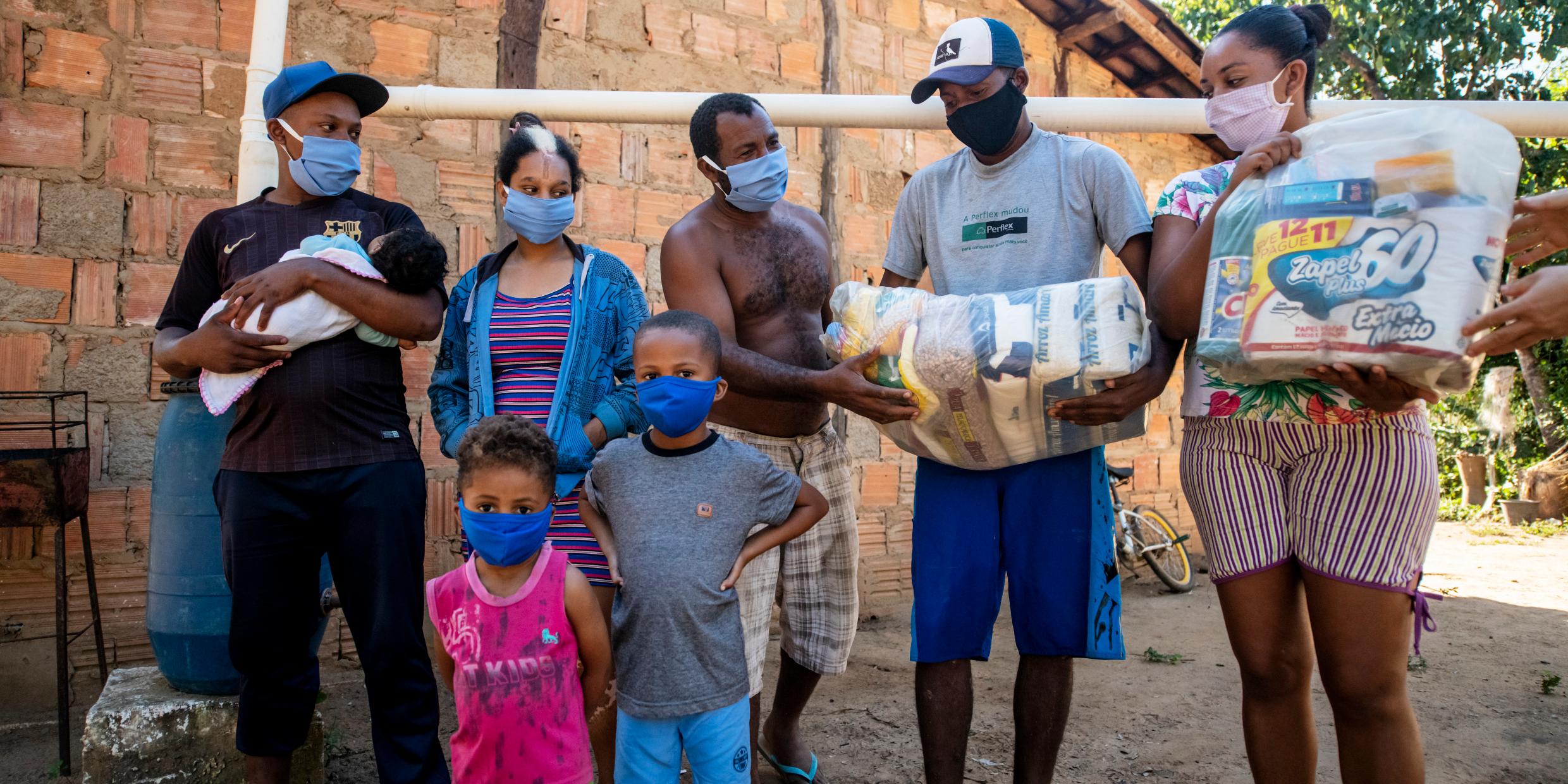 Eine brasilianische Familie mit Schutzmasken, Lebensmittelpaket und Hygieneartikeln, die sie von der CPP im Rahmen der Corona-Soforthilfe erhalten hat (Foto: Adveniat)