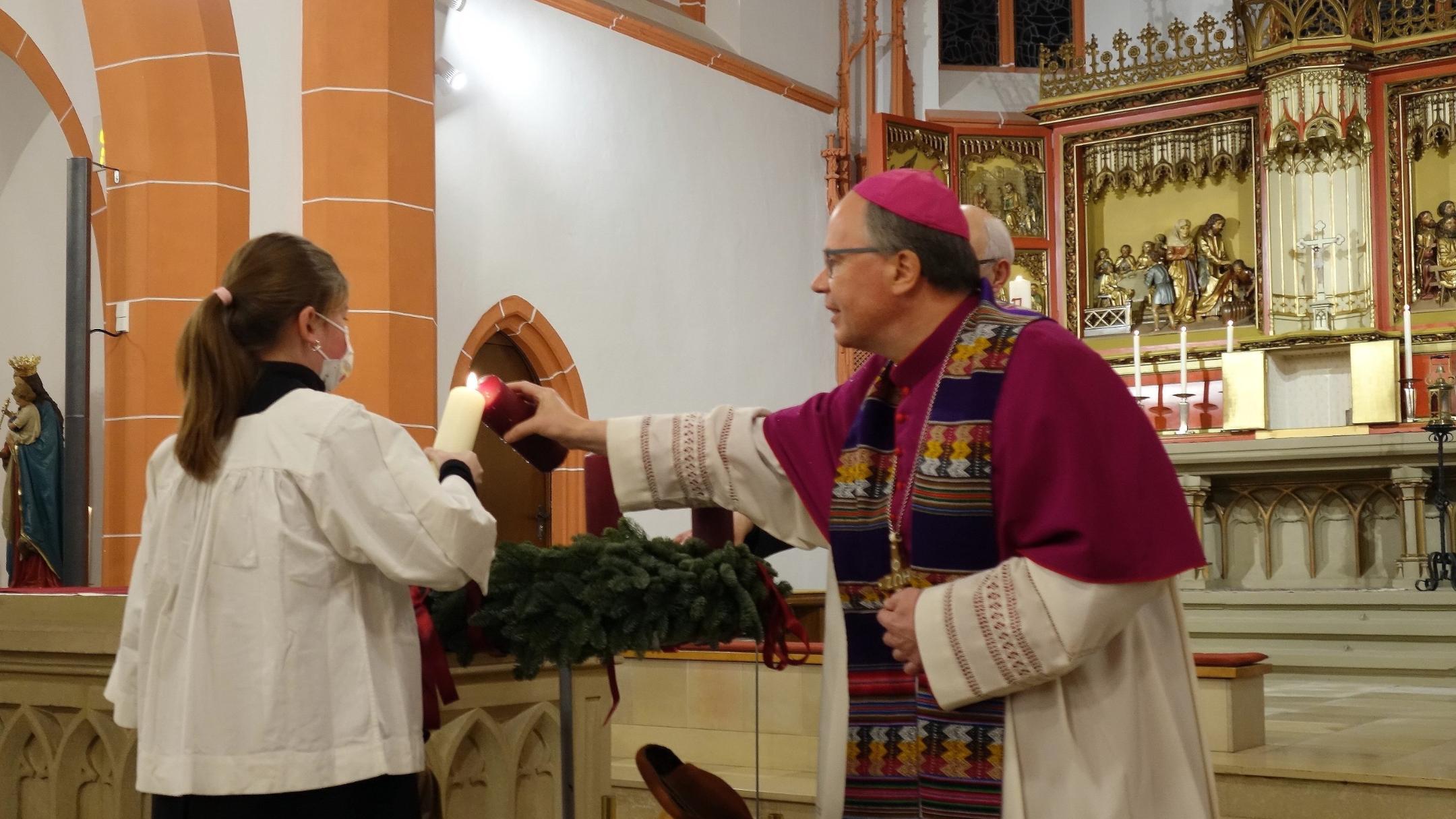 Zusammen mit einer Messdienerin zündet Bischof Ackermann die erste Kerze an (Fotos: J.Fröder/Bistum Trier)