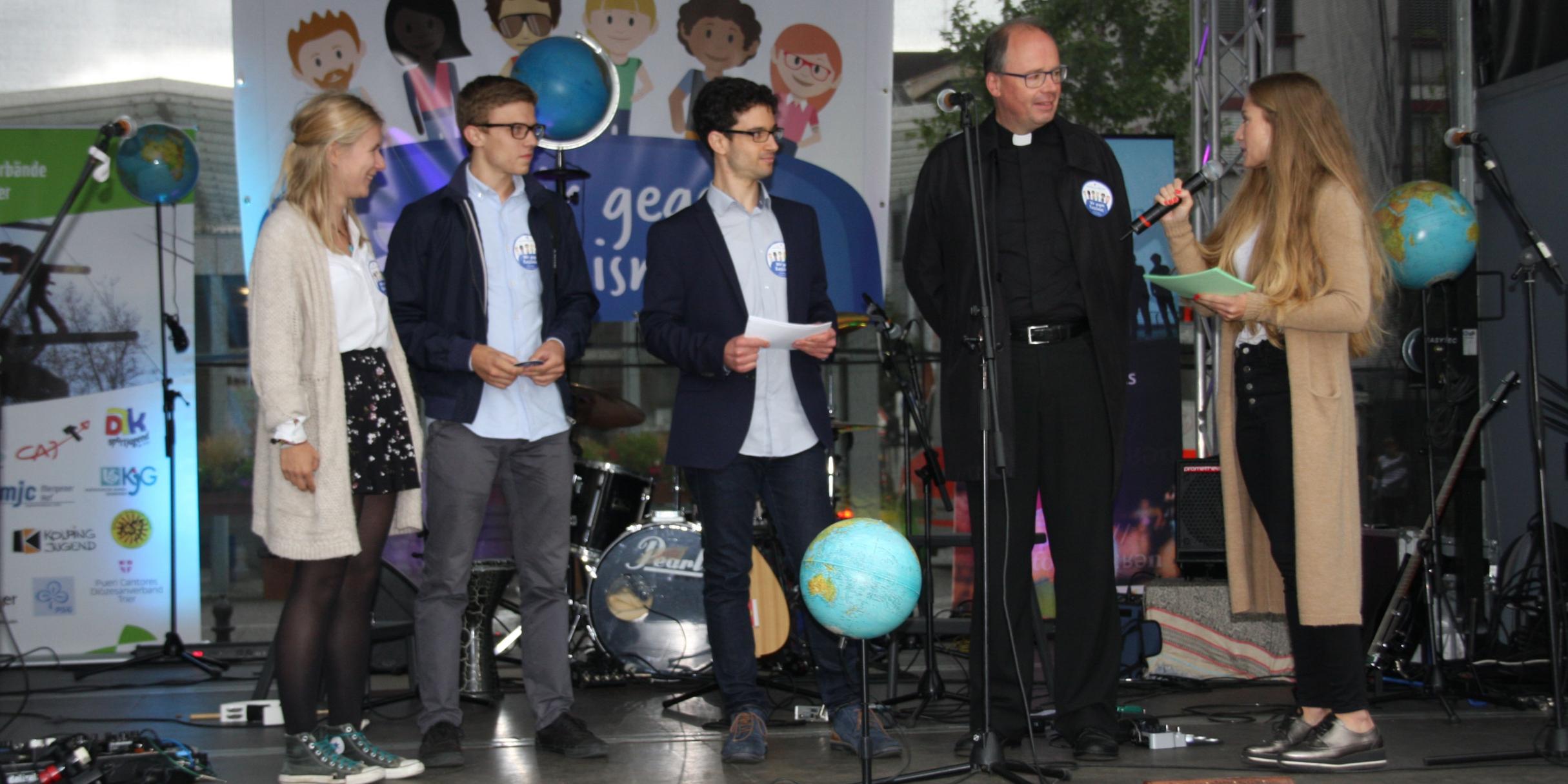 Bischof Ackermann beantwortet die Fragen der Moderatoren Lena Binz (rechts) und Christopher Hoffmann (Dritter v. links). Paulina und Johannes erklären den Ablauf der Aktion.