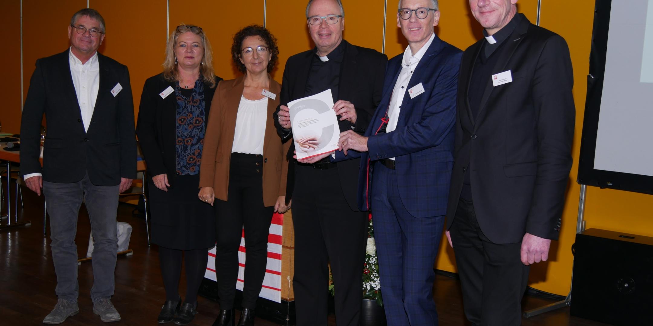 Dr. Michael Schröder vom DiCV Trier übergibt den Bericht an Bischof Dr. Stephan Ackermann (3. v.re.; Foto: DiCV Trier).
