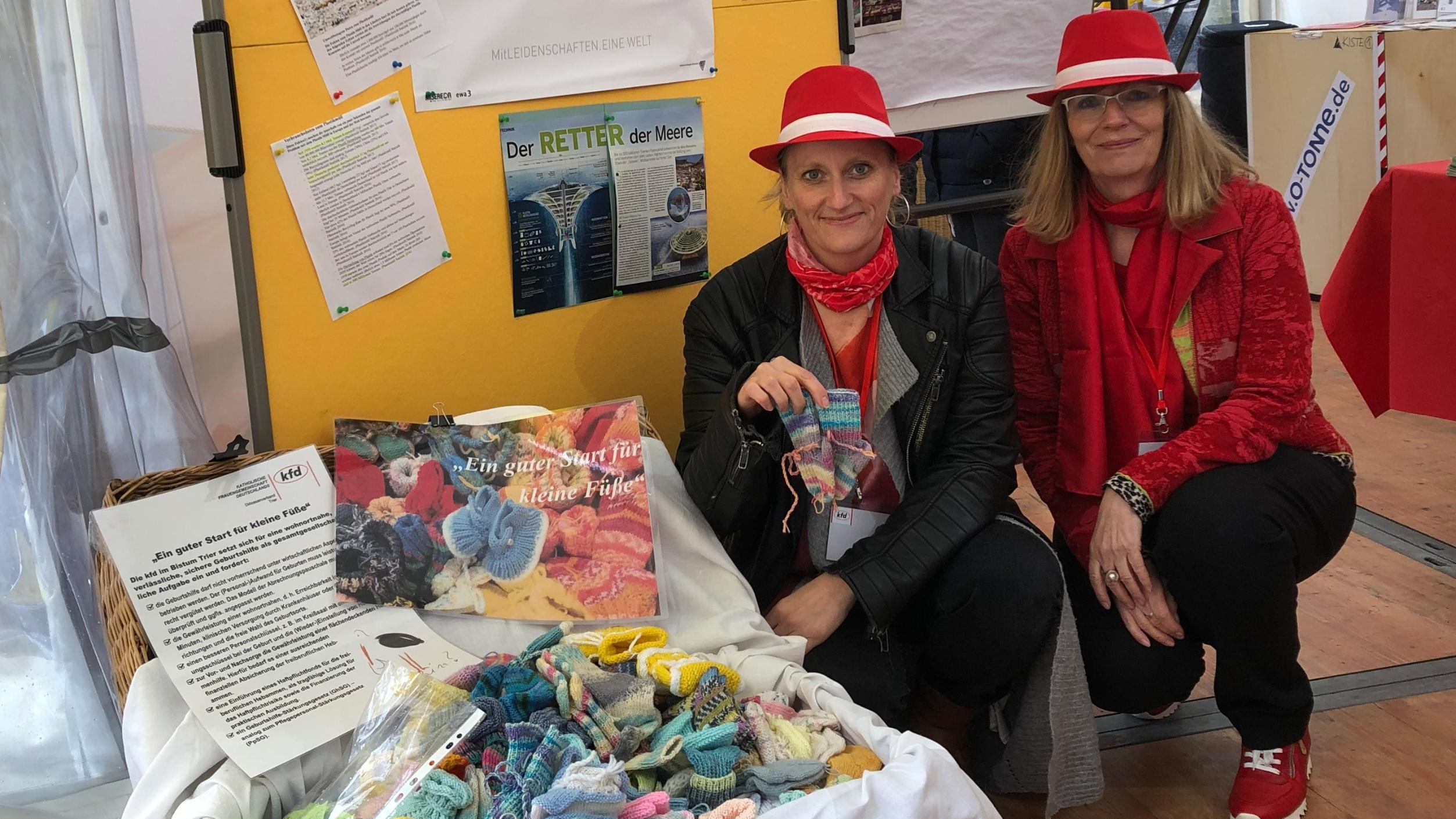 Anne Sturm und Monika Schuler (rechts) mit dem bis an den Rand gefüllten Korb voll gestrickter Babysöckchen der kfd-Frauen. gemeinsam mit Forderungen nach einer verbesserten Geburtshilfe werden diese symbolisch an die Gesundheitsministerinnen von RLP und Saarland überreicht