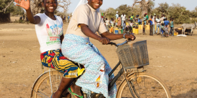 Plakat des missio-Sonntags - zwei Frauen auf dem Rad in der Steppe